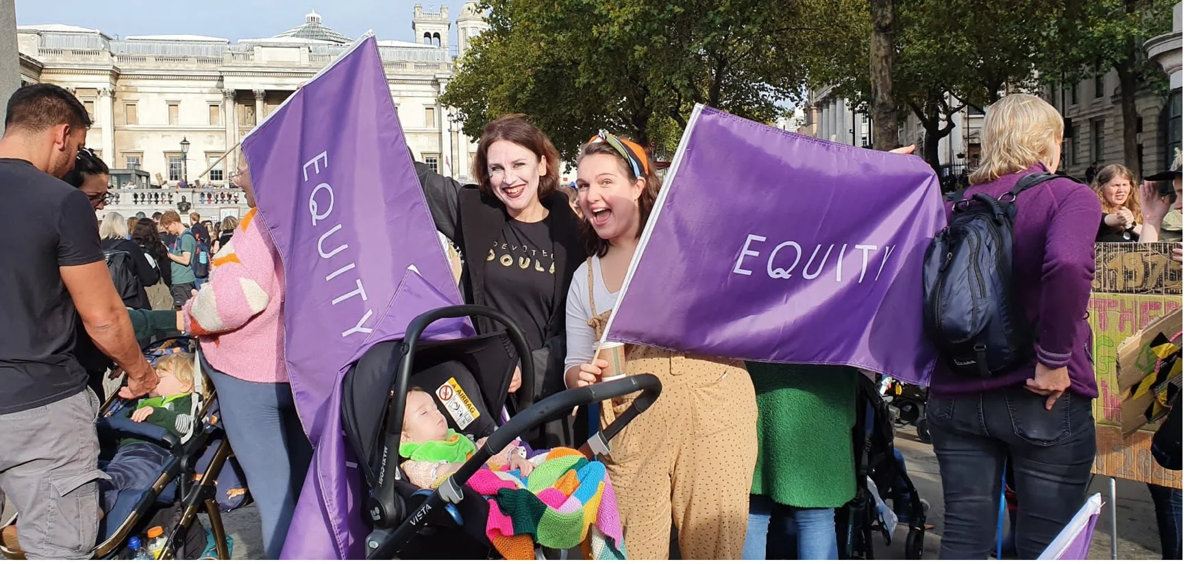 Members of Equity's Women's Committee holding flags at demo with baby