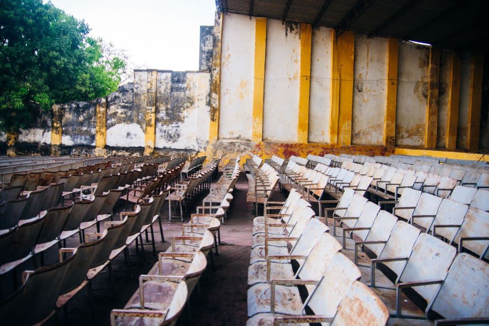 Photo shows rows of chairs in a dilapidated building without a roof
