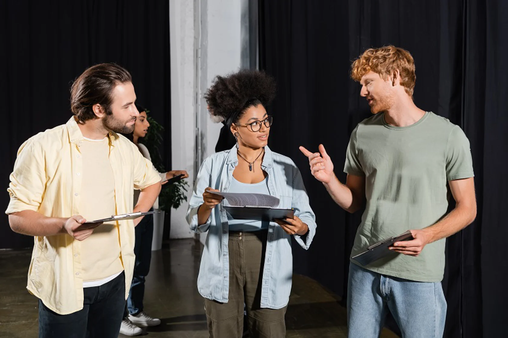 Three people with clip boards talking back stage