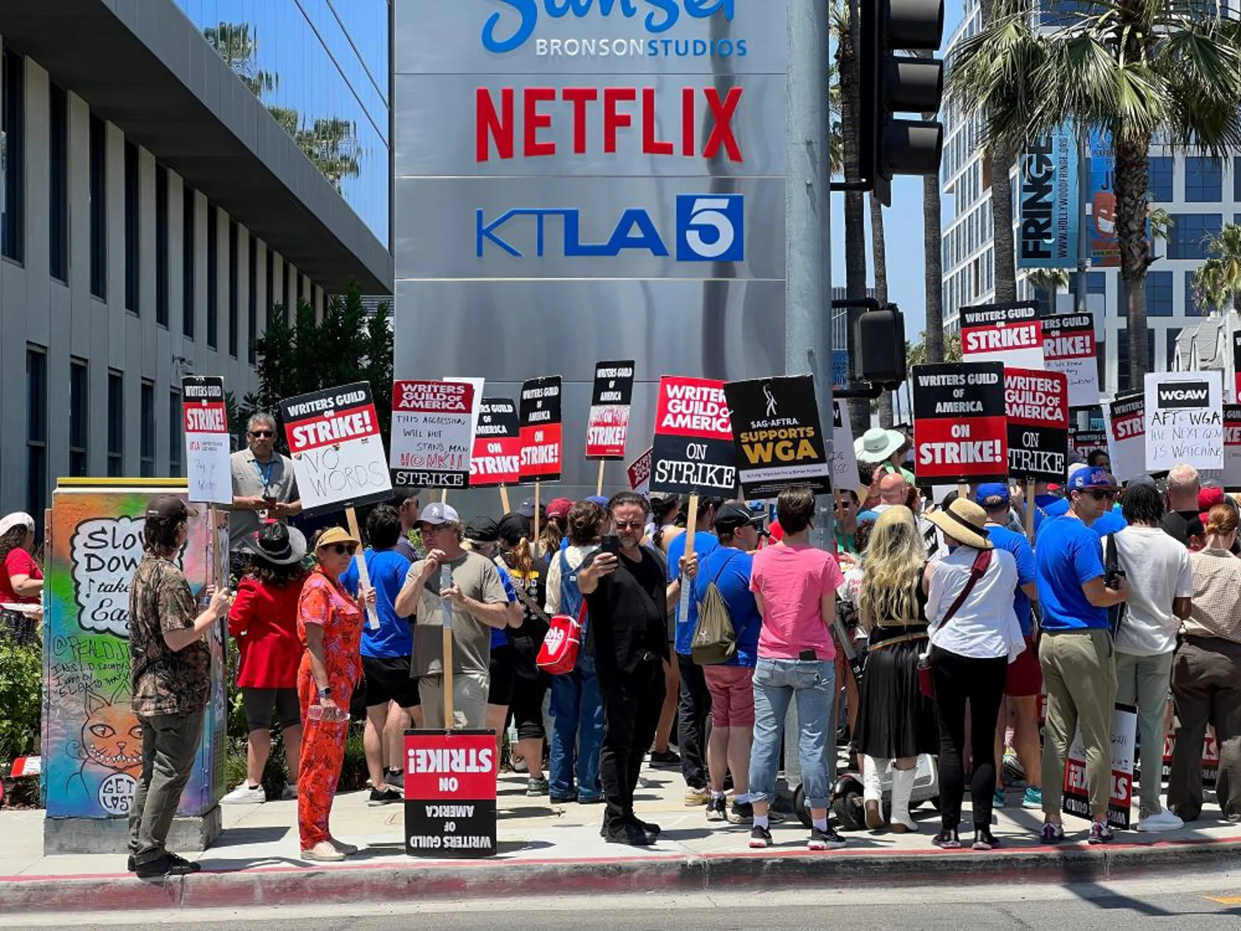 Photo shows WGA members protesting outside of Netflix headquarters holding placards