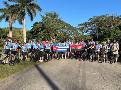 Large group of cyclists in front of mountains on a road in Cuba