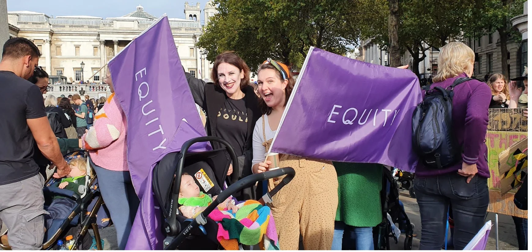 Members of Equity's Women's Committee holding flags at demo with baby