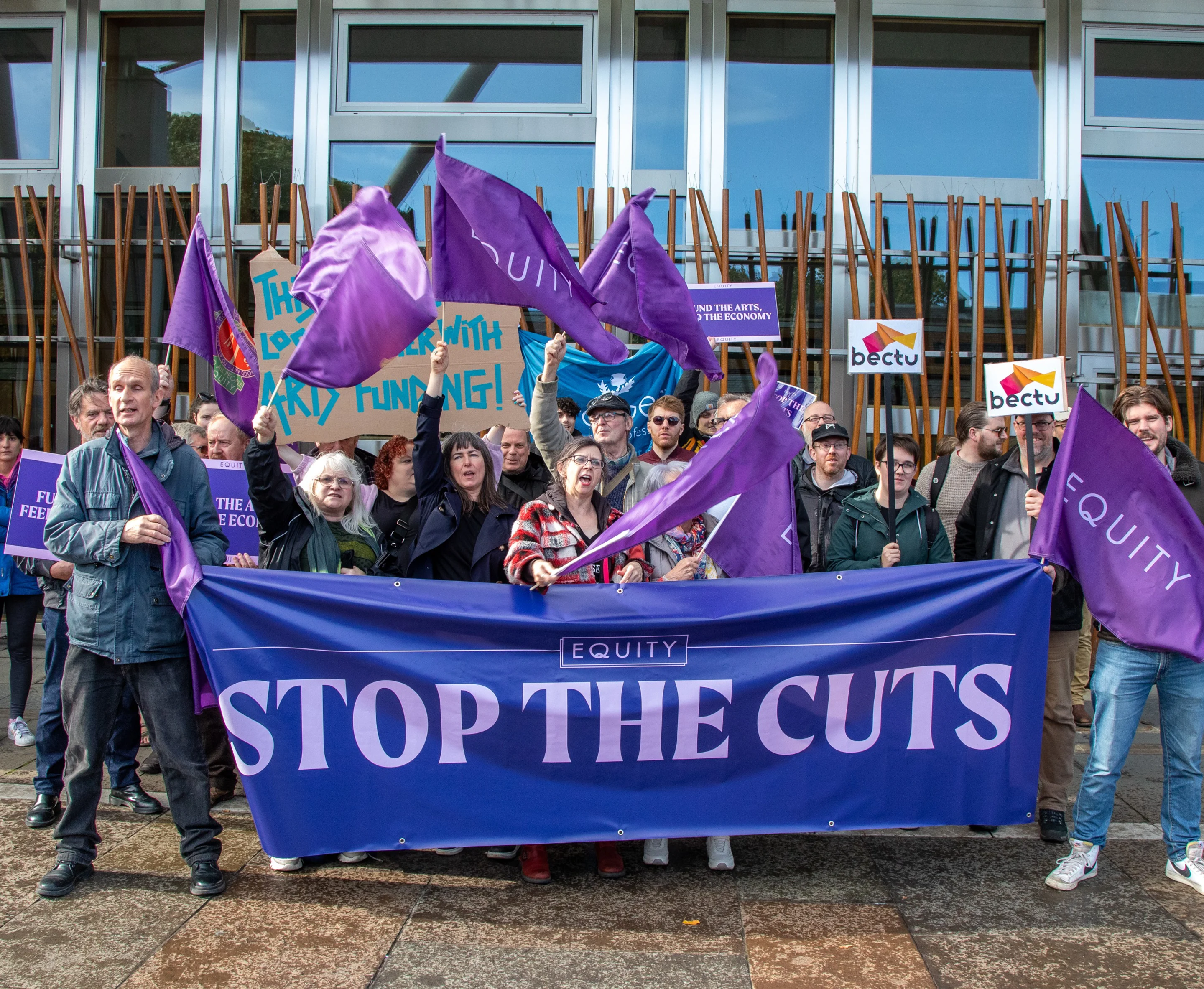 Group of Equity members with Stop the Cuts banners and flags at demo