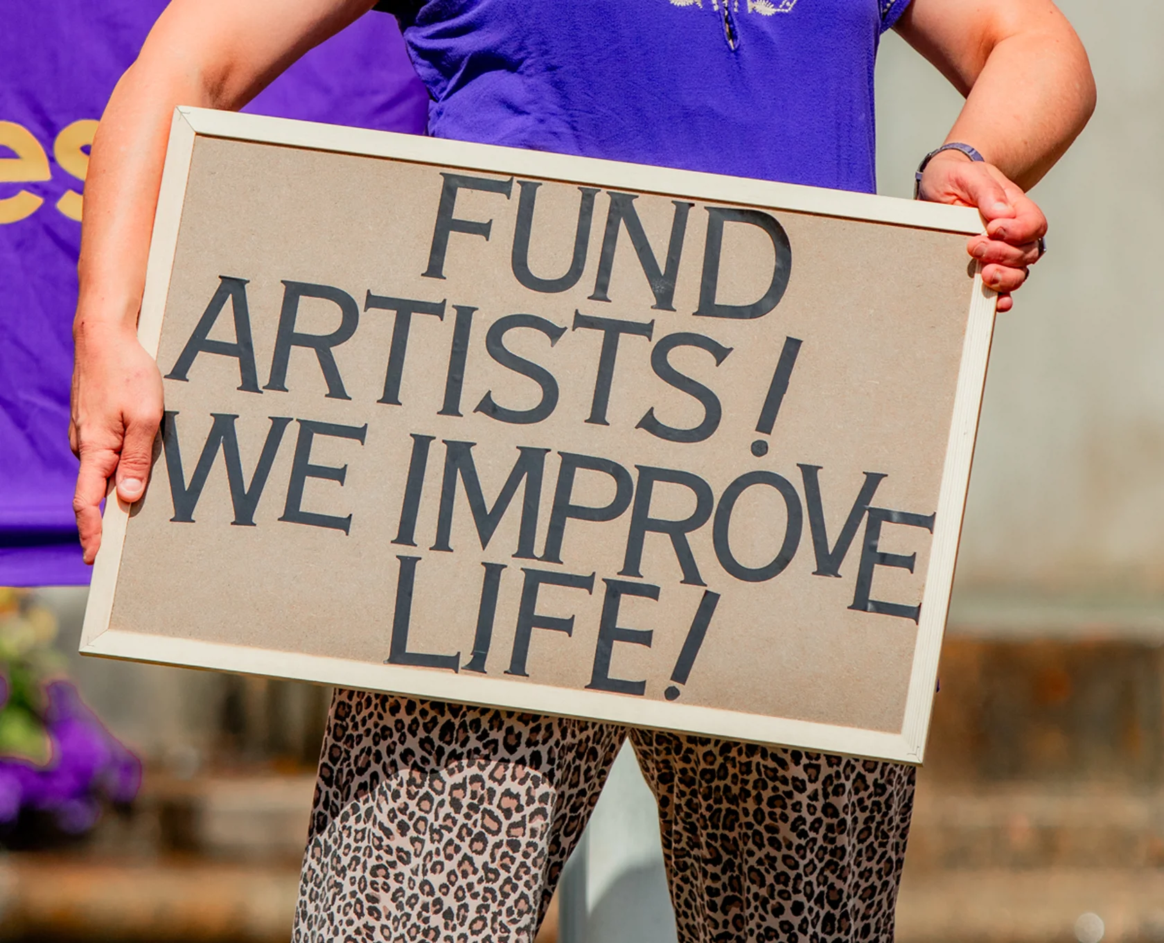 Sign saying "fund artists we improve life"