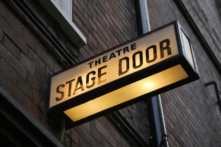 Photo shows lightbox on wall outside which reads 'theatre stage door'