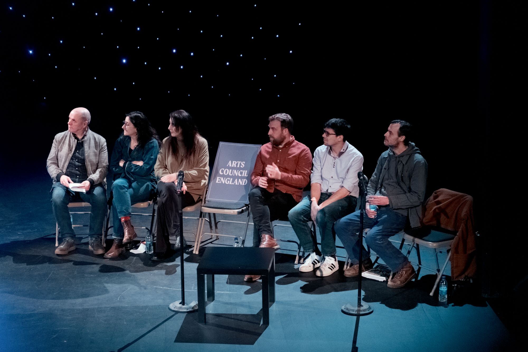 Photo shows on-stage speakers at Equity's 'Save Oldham Coliseum' event, their is an empty chair with an 'Arts Council England' sign