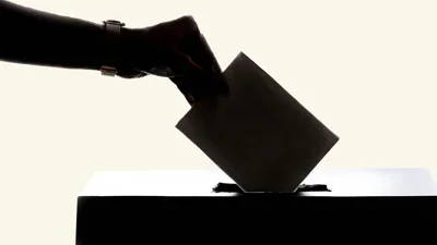 Hand putting a voting paper in a ballot box