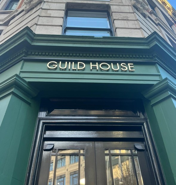 Photo shows building entrance, painted forest green with gold letters above the door that read 'Guild House'