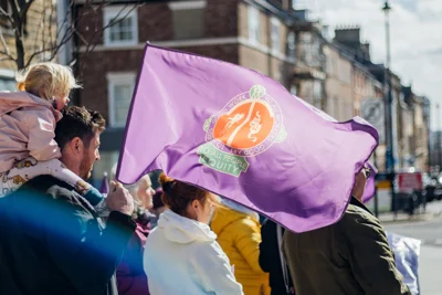 A child on a person's shoulders and Equity flag