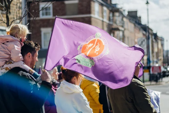 A child on a person's shoulders and Equity flag