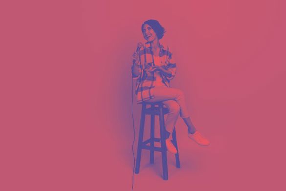 Photo shows woman sitting on a stool laughing, the photo has a red overlay