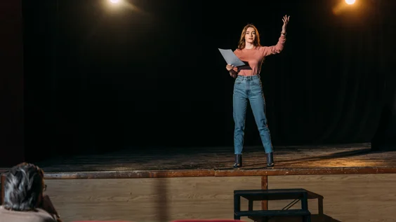 Woman reads script onstage during audition
