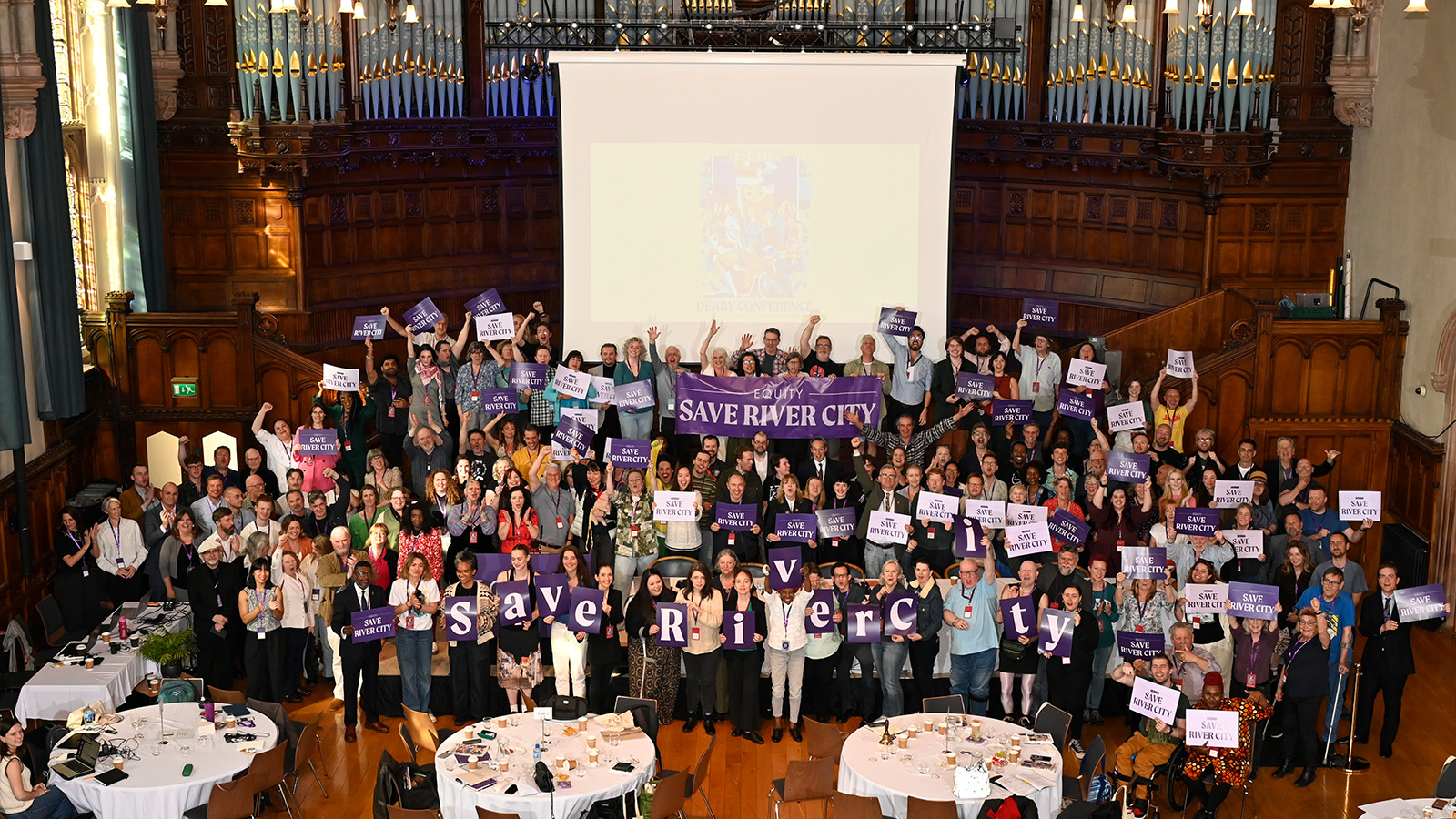 Members at Equity conference hold Save River City signs. 