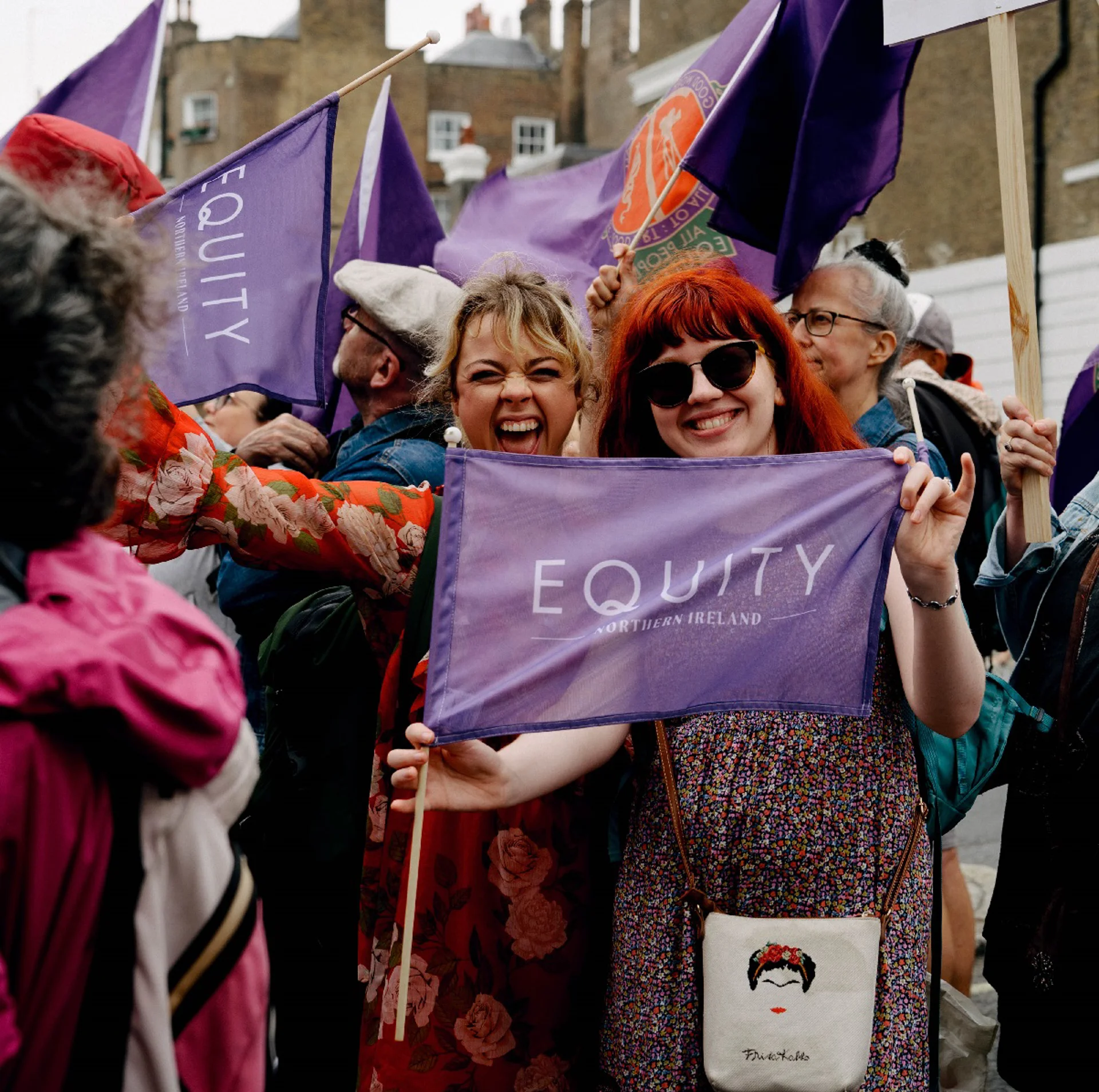 Two women Equity members holding Equity Northern Ireland flag at demo