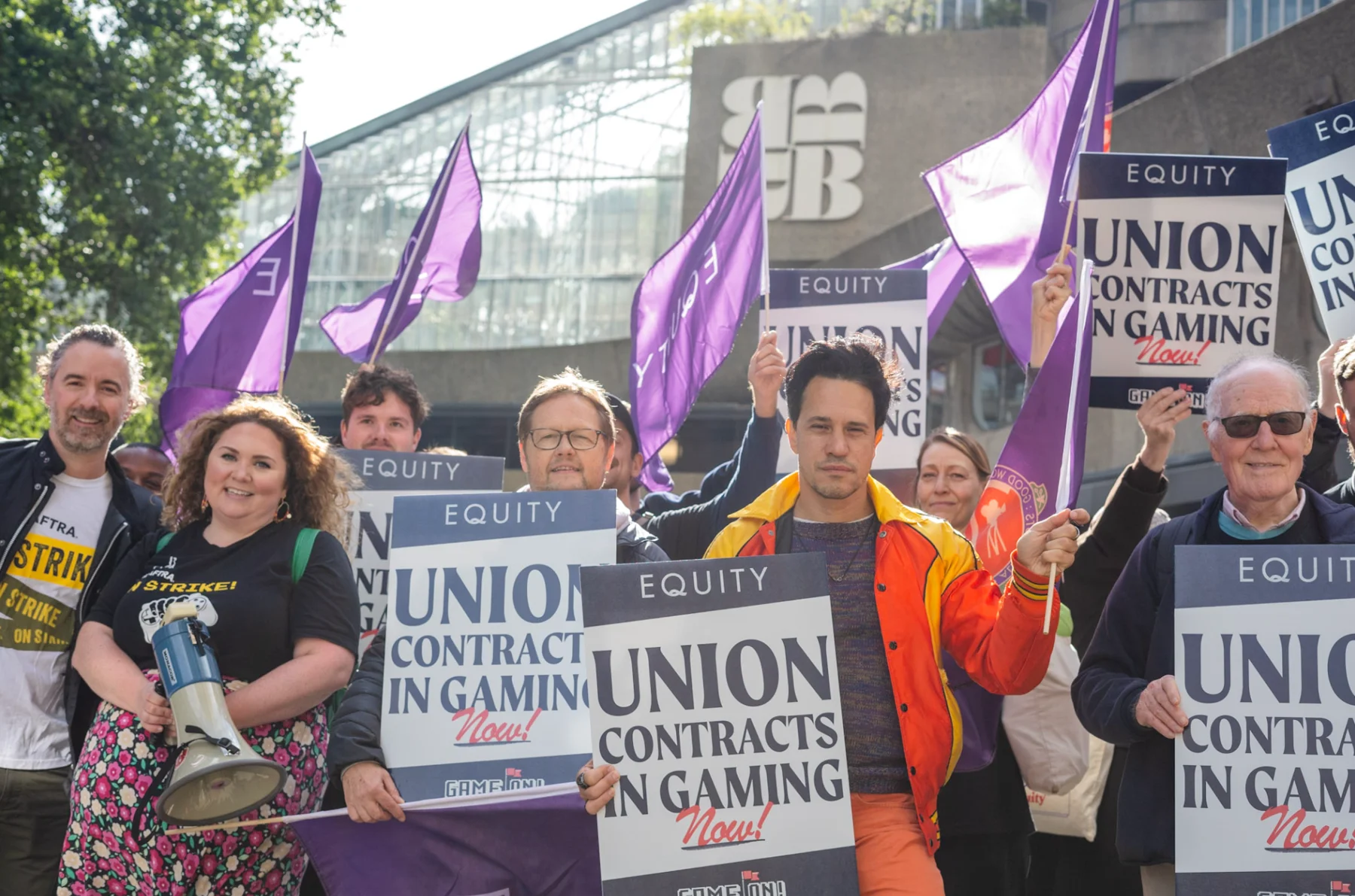 Equity members with banners that say "Union contracts in gaming now"