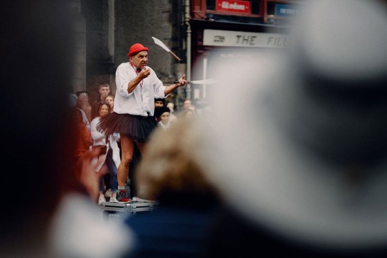 Photo shows crowd at Edinburgh Fringe Festival watching an older man knife juggling