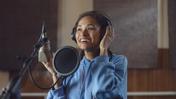 Woman audio artist at work in studio speaking into microphone