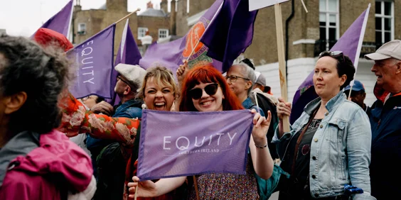 Two women Equity members holding Equity Northern Ireland flag at demo