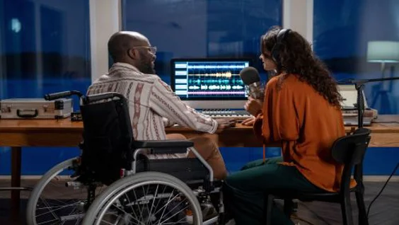Man using wheelchair in a studio with a woman with microphone